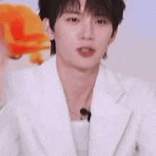a close up of a young man wearing a white jacket with a microphone in his mouth .