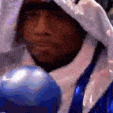 a man wearing blue boxing gloves and a white jacket