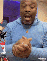 a man wearing a blue hoodie is clapping his hands in a video