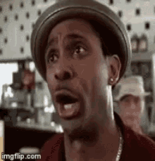 a man wearing a hat and earrings is making a funny face .