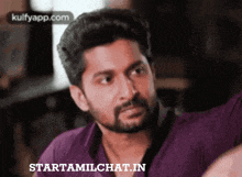 a man with a beard wearing a purple shirt with starttamilchat.in written on the bottom right