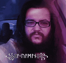 a man with glasses and a beard is sitting in a car with the letters of nmf on the bottom