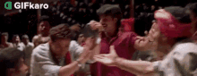 a group of people are dancing in a room with a crowd behind them .