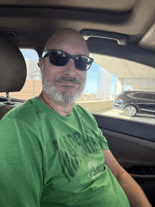 a man wearing sunglasses and a green t-shirt that says wilderness on it