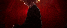 a man in a suit is standing in front of a table with candles on it in a dark room .