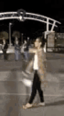 a blurry picture of a woman walking down the street at night .
