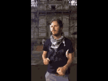 a man wearing a scarf around his neck stands in front of a building under construction