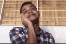 a man in a plaid shirt is sitting on a couch with his head resting on his hand .