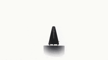 a black metronome is sitting on top of a white podium .