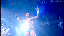 a man without a shirt is standing on a stage with his arms outstretched