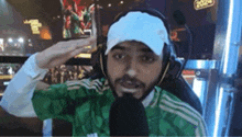 a man wearing headphones , a green shirt , and a white hat is saluting .