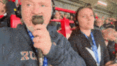 a man is holding a microphone with the letter r on his sweatshirt
