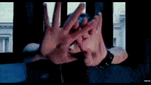 a person is covering their face with their hands in front of a window