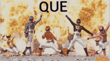 a group of power rangers are standing in front of a fire and the word que is visible