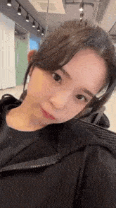 a close up of a woman wearing a black hoodie making a funny face in a room .