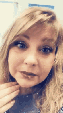 a close up of a woman 's face with her hand on her chin .