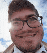 a man with glasses and a beard smiles with the sun shining on his face