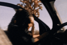 a blurry picture of a woman driving a car with the door open