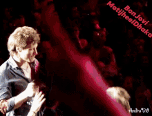 a man is holding a woman 's hand in front of a crowd and the words bon jovi motijheel chaka are visible
