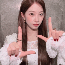 a woman with long hair is making a heart with her fingers