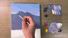 a person is painting a mountain landscape on a canvas with made in animotica written on the bottom