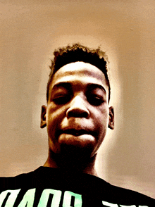 a young man wearing a black shirt that says ' and ' on it looks at the camera with his eyes closed