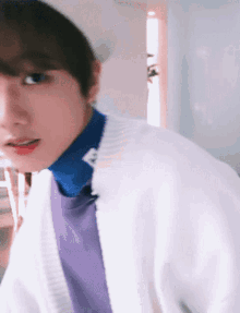 a blurry photo of a person wearing a white sweater and a purple shirt