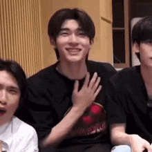 a group of young men are sitting next to each other in a room and smiling .