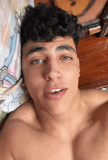 a young man with curly hair is laying on a bed