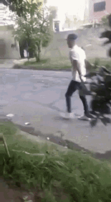 a man is riding a motorcycle down a street while another man watches .