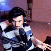 a man wearing headphones is sitting in front of a microphone in a living room .