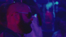 a man with a beard wears sunglasses and says ale
