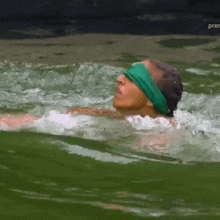 a man in a green headband is swimming in a body of water