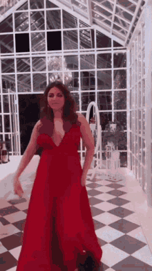 a woman in a red dress is standing in a room with a checkered floor .