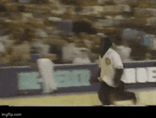 a man is running on a baseball field in front of a crowd .