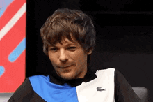 a man wearing a blue and white shirt with a lacoste logo on it .