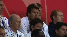 a group of men are sitting in a stadium and one of them is wearing a shirt with the word england on it