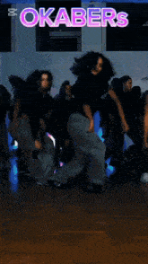 a group of people are dancing in front of a sign that says okabers on it