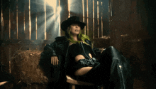 a woman with green hair and a cowboy hat sits in a chair