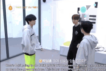 a group of young men are standing in a room and talking