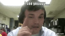 a man is making a funny face while sitting in front of a camera and says `` i see youuu '' .