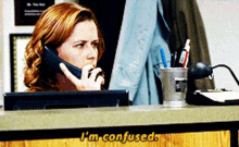a woman talking on a cell phone with i 'm confused written on the counter