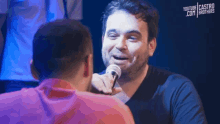 a man holding a microphone in front of another man with youtube castro brothers written on the bottom right