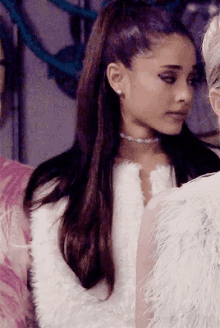 ariana grande is wearing a white fur coat and pearl earrings .