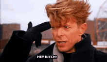 a man with red hair is pointing his finger at his head and saying hey bitch .