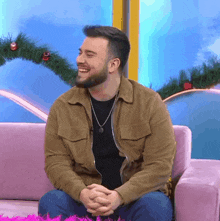 a man with a beard is sitting on a pink couch