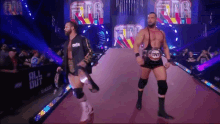 two wrestlers are walking down a red carpet with the word tnt on it
