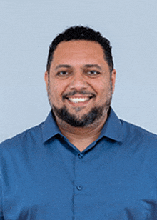 a man with a beard wearing a blue shirt is smiling