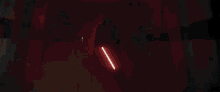 darth vader is holding a lightsaber in a dark room and shooting it .