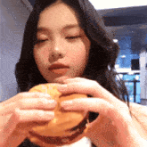 a woman is holding a hamburger in her hands and eating it
